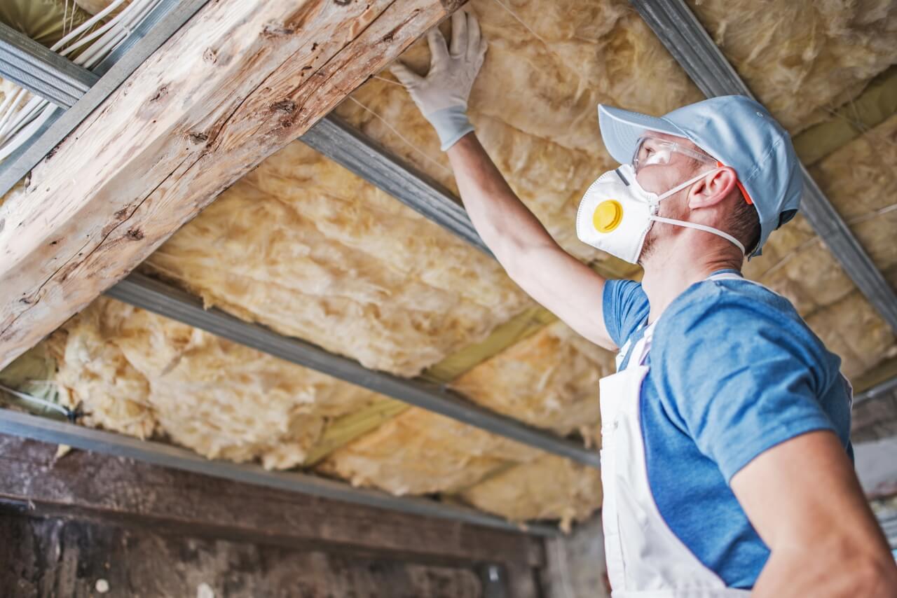 checking-insulation-in-attic A man in a blue shirt with a mask is checking attic insulation. The right insulation will help you heat your home efficiently.