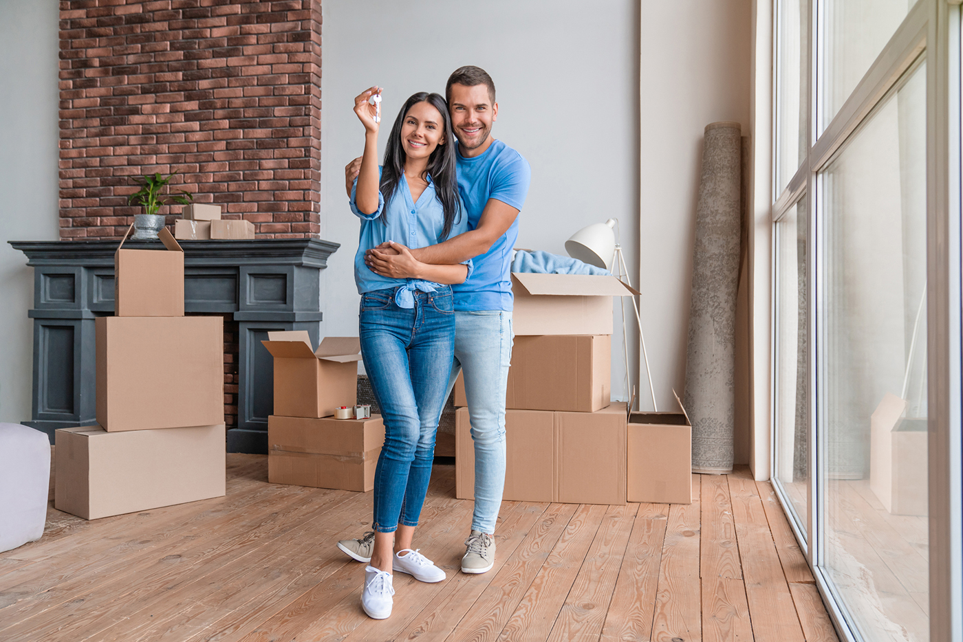 Portrait of young couple with keys in new apartment